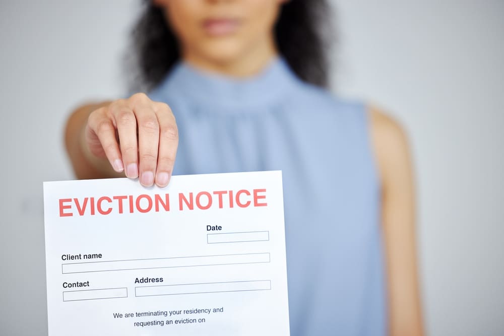 Woman holding up a piece of paper that says "eviction notice."